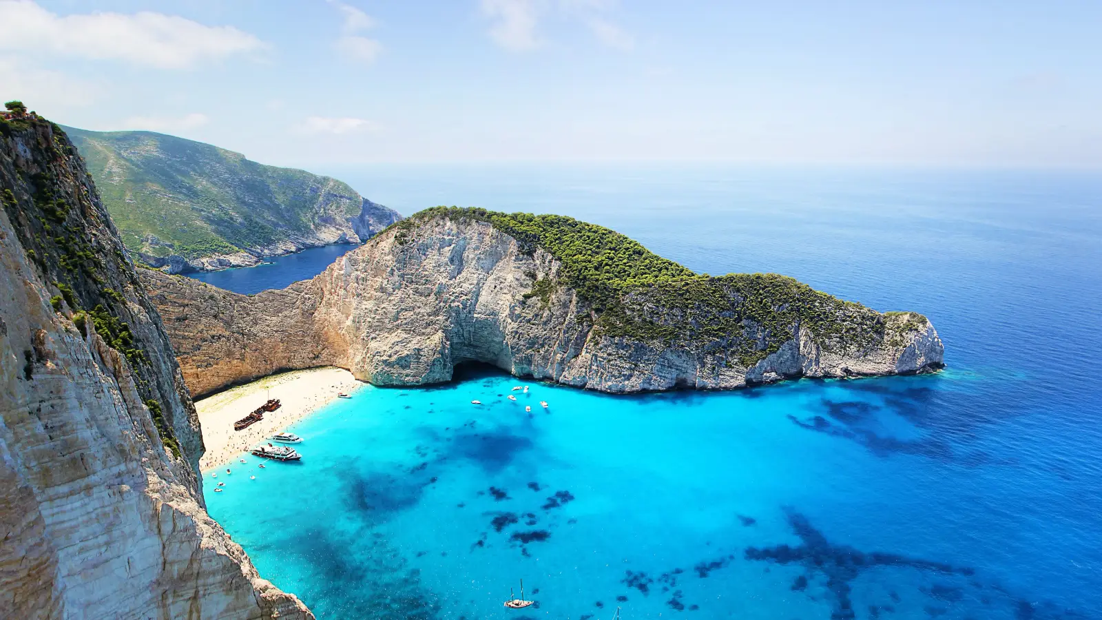 Boats on turquoise water at Navagio beach, a Greece Golden Visa lifestyle destination