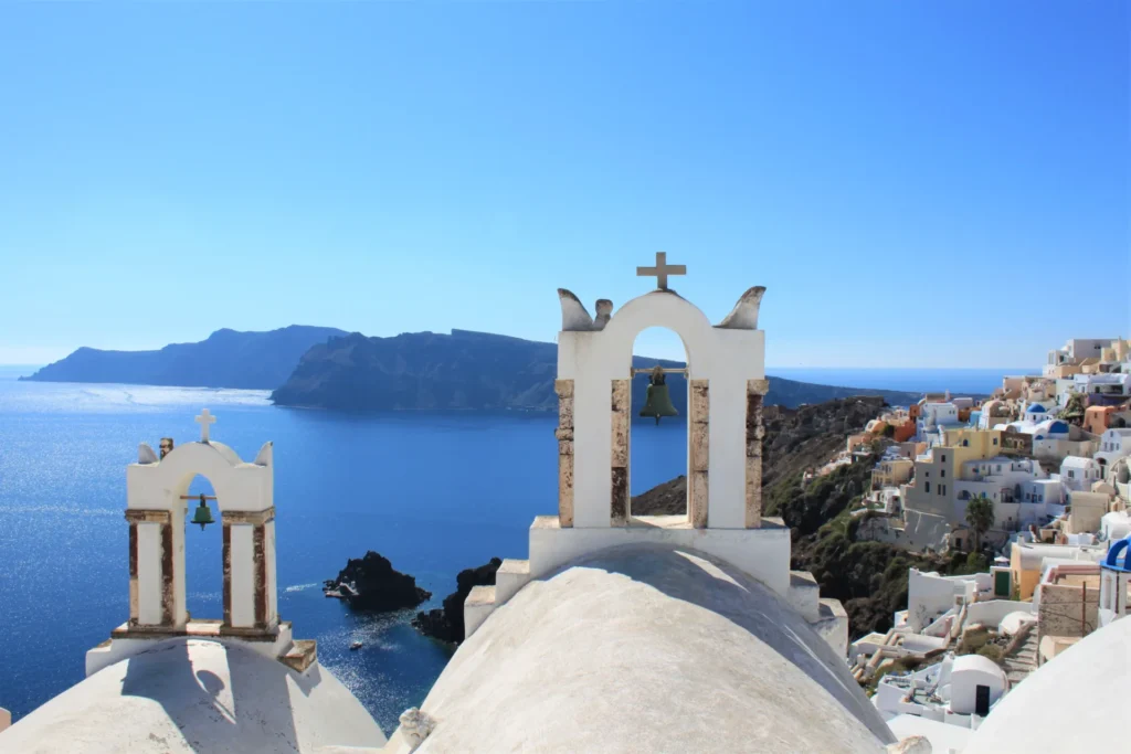Whitewashed church bell towers overlooking the caldera and blue sea in Santorini, Greece
