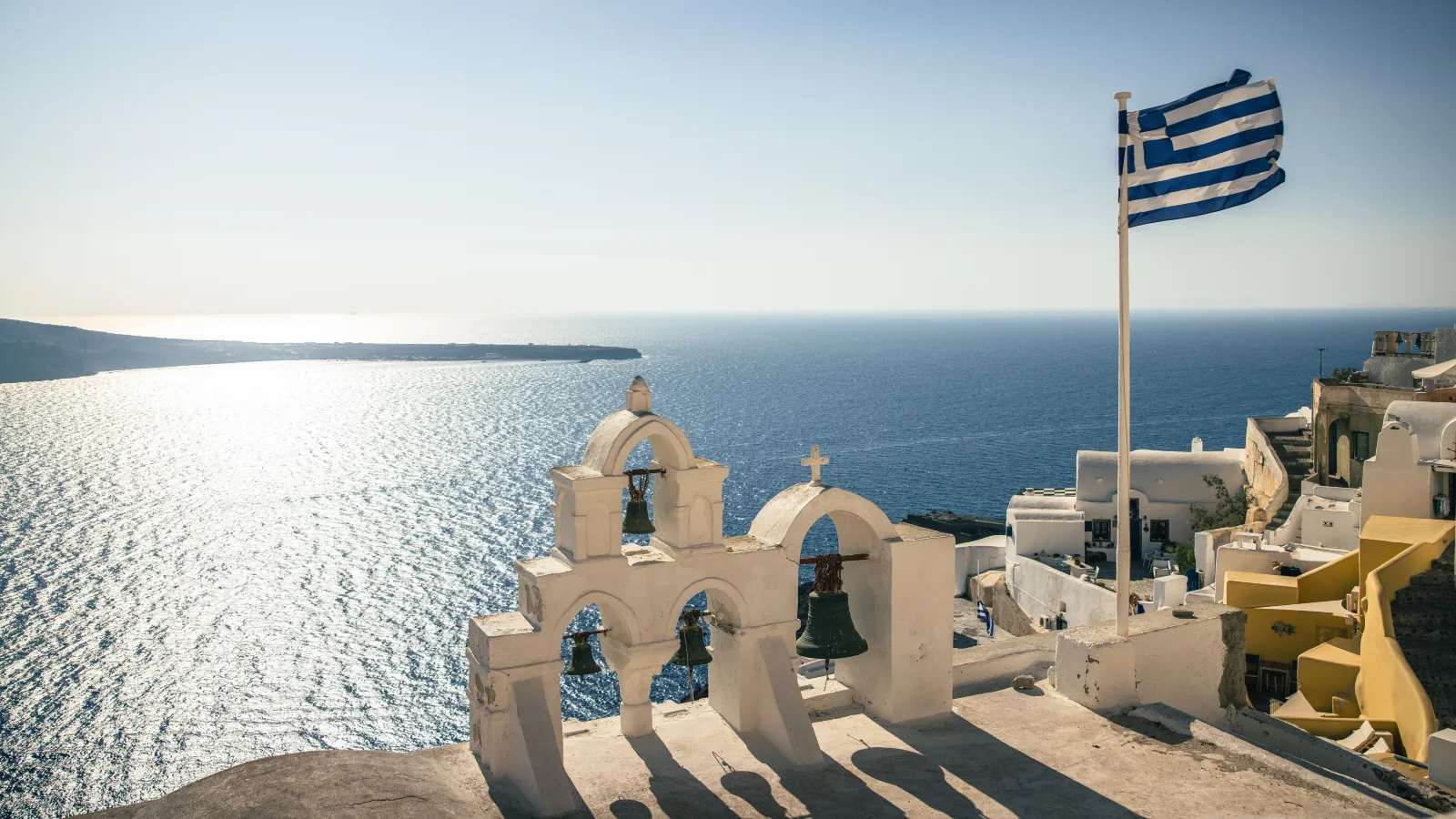 Greek flag over a Santorini bell tower, a lifestyle destination for non-dom tax residents